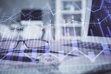 Financial chart hologram with glasses on the table background. Concept of business. Double exposure.