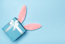 Easter Rabbit Fluffy Ears With A Gift Box On A Blue Background. Copy Space Top View Flat Lay