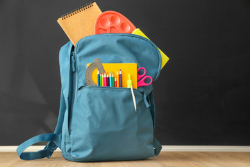 School backpack with stationery on table in classroom