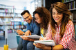 © NDABCREATIVITY - Group of happy students reading books and preparing to exam in library