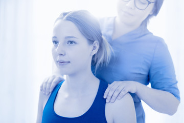 Wall Mural - Female physiotherapist or a chiropractor examining patients back. Physiotherapy, rehabilitation concept.