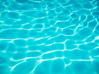 full frame background of rounded wave patterns sparkling on the bottom of a bright blue swimming poo