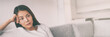 © Maridav - Bored young Asian woman depressed waiting on sofa at home panoramic banner.