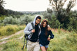 © bedya - Young couple with backpacks on their backs in the forest. Loving man kisses his beautiful girlfriend on a hike in the woods
