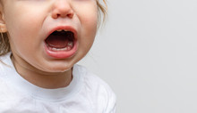 Portrait Of A Baby Toddler Child Crying. Kid Opened His Mouth Wide, In Which Fangs Erupt And Saliva Flows. The Child Has Toothaches And A Crisis Of 1 Year Of Life. Copy Space Text, Banner, Close-up