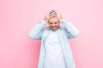 young handsome man feeling stressed and frustrated, raising hands to head, feeling tired, unhappy and with migraine against flat wall