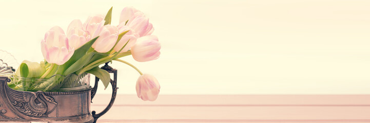 Still life with pink tulip bouquet in a vintage vase on panoramic background with copy space