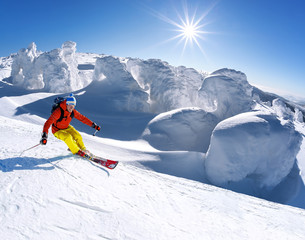 Wall Mural - Skier skiing downhill in high mountains against blue sky