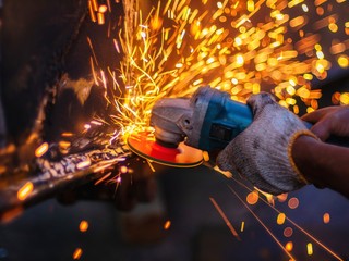 Soft of focus. worker grinding cutting metal sheet with grinder machine overwrites the master of welding seams angle grinder and sparks. 