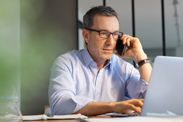 Business manager working in office talking on phone