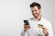 © Drobot Dean - Businessman using mobile phone holding credit card.