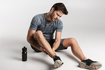 Tired young sportsman resting on a floor isolated