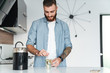 © Drobot Dean - Smiling young bearded man making cup of tea