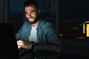 Poster - Smiling young man working on laptop computer