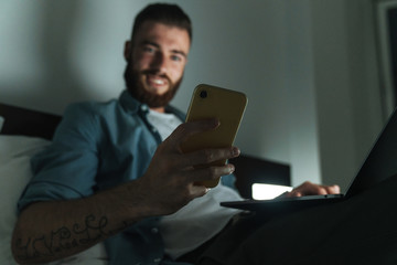 Poster - Smiling young bearded man laying on bed at home