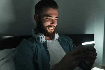 Poster - Smiling young bearded man laying on bed at home