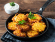 Potatoes pancakes latkes, flapjacks, hash brown or potato vada with white greek yoghurt or sour cream on brown wooden table. Copy space for text.