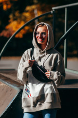 Wall Mural - Stylish model girl at skate park in glasses with waist bag