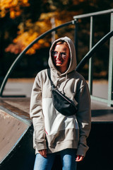 Wall Mural - Stylish model girl at skate park in glasses with waist bag