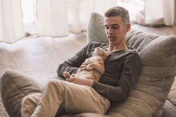 Handsome teenage guy relaxing on modern soft couch at home in living room