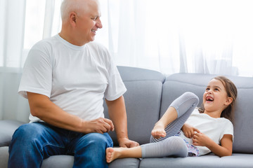 Wall Mural - Portrait Of Grandfather With Granddaughter Relaxing Together On Sofa