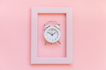 Ringing twin bell vintage alarm clock in pink frame isolated on pink pastel colorful trendy background. Rest hours time of life good morning night wake up awake concept. Flat lay top view copy space