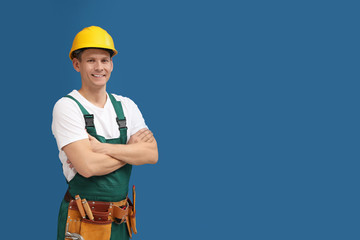 Poster - Handsome carpenter with tool belt on blue background. Space for text