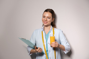 Poster - Nutritionist with glass of juice and clipboard on light grey background