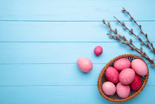 Pink Easter Eggs In Basket And Willow Branches On Blue Background