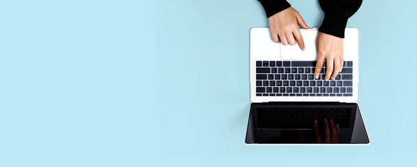 Person using a laptop computer on a solid color background