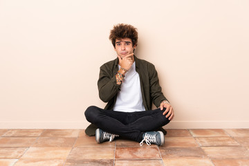 Wall Mural - Young caucasian man sitting on the floor thinking