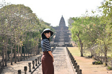 Young Asian Woman In White Hat And Striped Shirt Is Exploring The Ancient Ruins Of Prasat Hin Phanom Rung Temple In Buriram, Thailand.