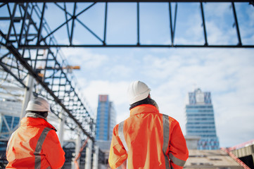 Rear view of engineers standing outdoors on construction site.