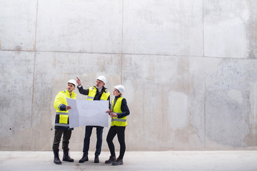 a group of engineers standing against concrete wall on construction site.