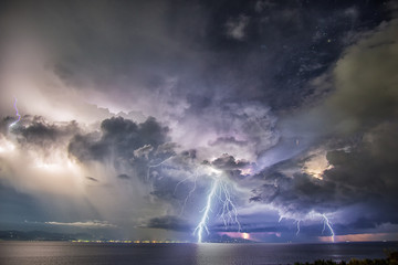 Night time picture of tropical thunder storm with dramatic clouds and lightning striking the sea on Bali, Indonesia