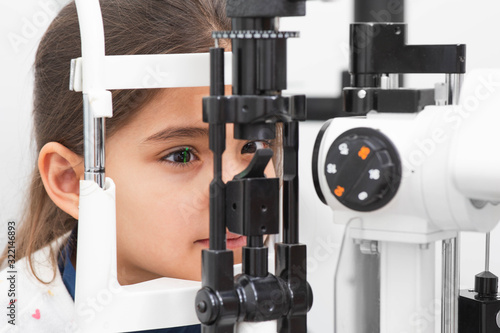 Fotomural Little girl patient checking vision with special eye equipment