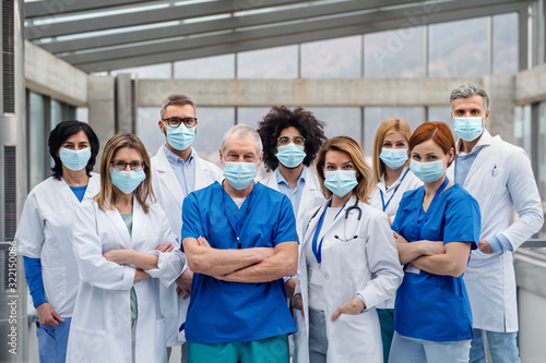 Cuadros en Lienzo Group of doctors with face masks looking at camera, corona virus concept