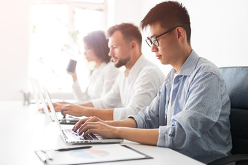 Asian developer working near colleagues in office