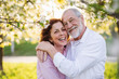 Beautiful senior couple in love outside in spring nature, hugging.
