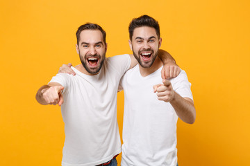 laughing young men guys friends in white blank empty t-shirts posing isolated on yellow orange backg