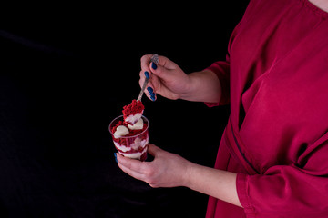 Wall Mural - Dessert red velvet in a small transparent cup. The girl's hands on a dark background.