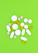 Different vitamins, pills and capsules on a green background.