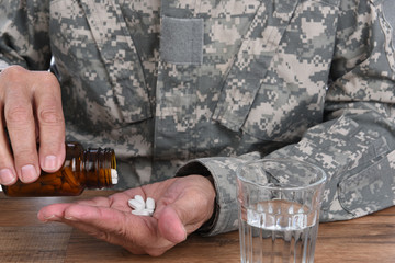 Military Drug abuse concept. Closeup of soldier with taking pills to treat his PTSD symptoms.