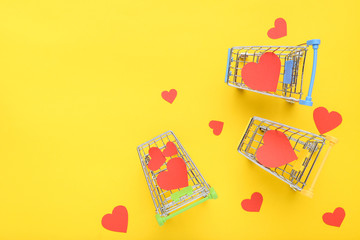 Wall Mural - Paper hearts with shopping carts on yellow background