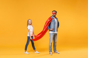 Wall Mural - Bearded man in casual clothes Superman costume with shocked child baby girl. Father little kid daughter isolated on yellow background. Love family parenthood childhood concept. Stand with arms akimbo.