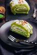 Green matcha cake rolls on black plate on dark background. Selective focus