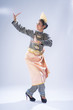 A beautiful Malaysian traditional female dancer performing a cultural dance routine in a traditional outfit on a stage. Full length portrait.
