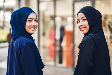 Wall Mural - Portrait of happy arabic two friend muslim woman with hijab dress smiling and look at camera at store