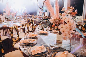 Wedding decorations. Festive table decorated with compositions of colored flowers. On the tables are plates, glasses, candles and cutlery