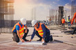 © Panumas - Structural engineer and architect working with blueprints discuss at the outdoors construction site.